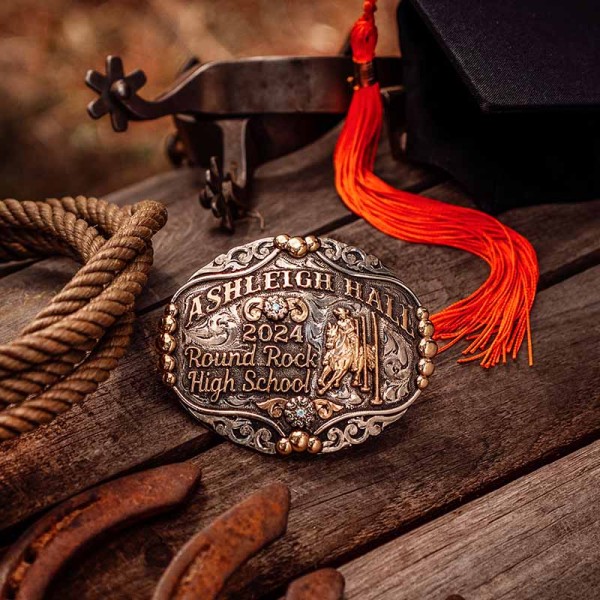 A custom rodeo belt buckle for Round Rock High School featuring a pole bending cowgirl figure